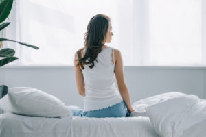 woman sitting on a bed facing window